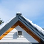 Winter exterior of a Canadian home roof with a continuous ridge vent and ice-free eaves under light snow, illustrating efficient attic ventilation and roof protection.