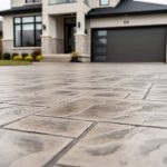 Close, low-angle view of a stamped concrete driveway with realistic stone and brick-like texture in front of a modern Mississauga home.